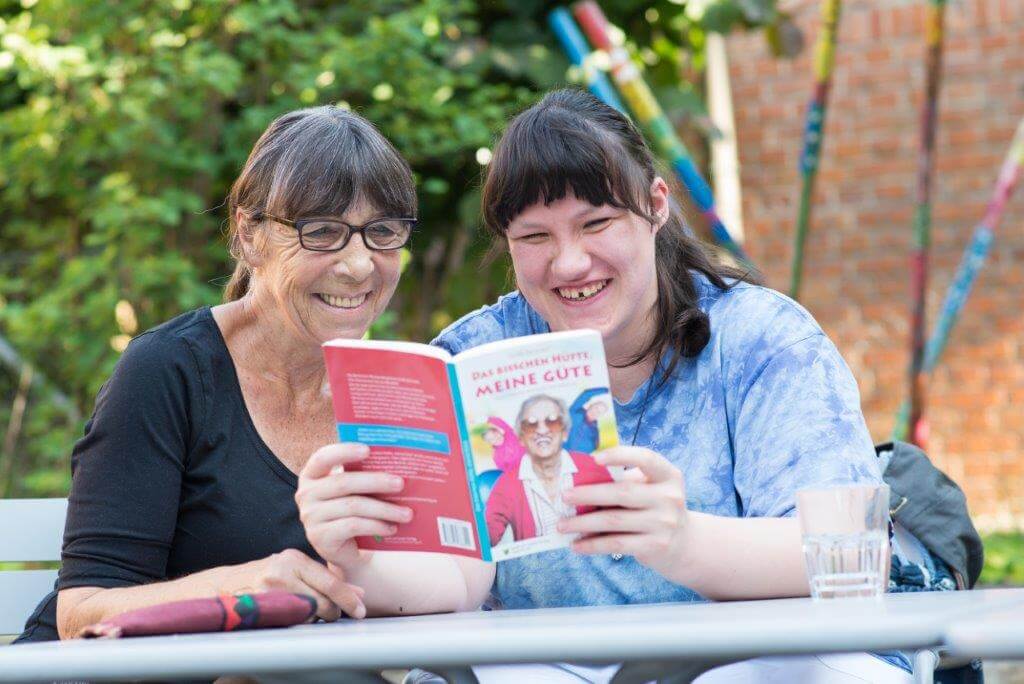 Zwei Personen lesen ein Buch. Sie lächeln.